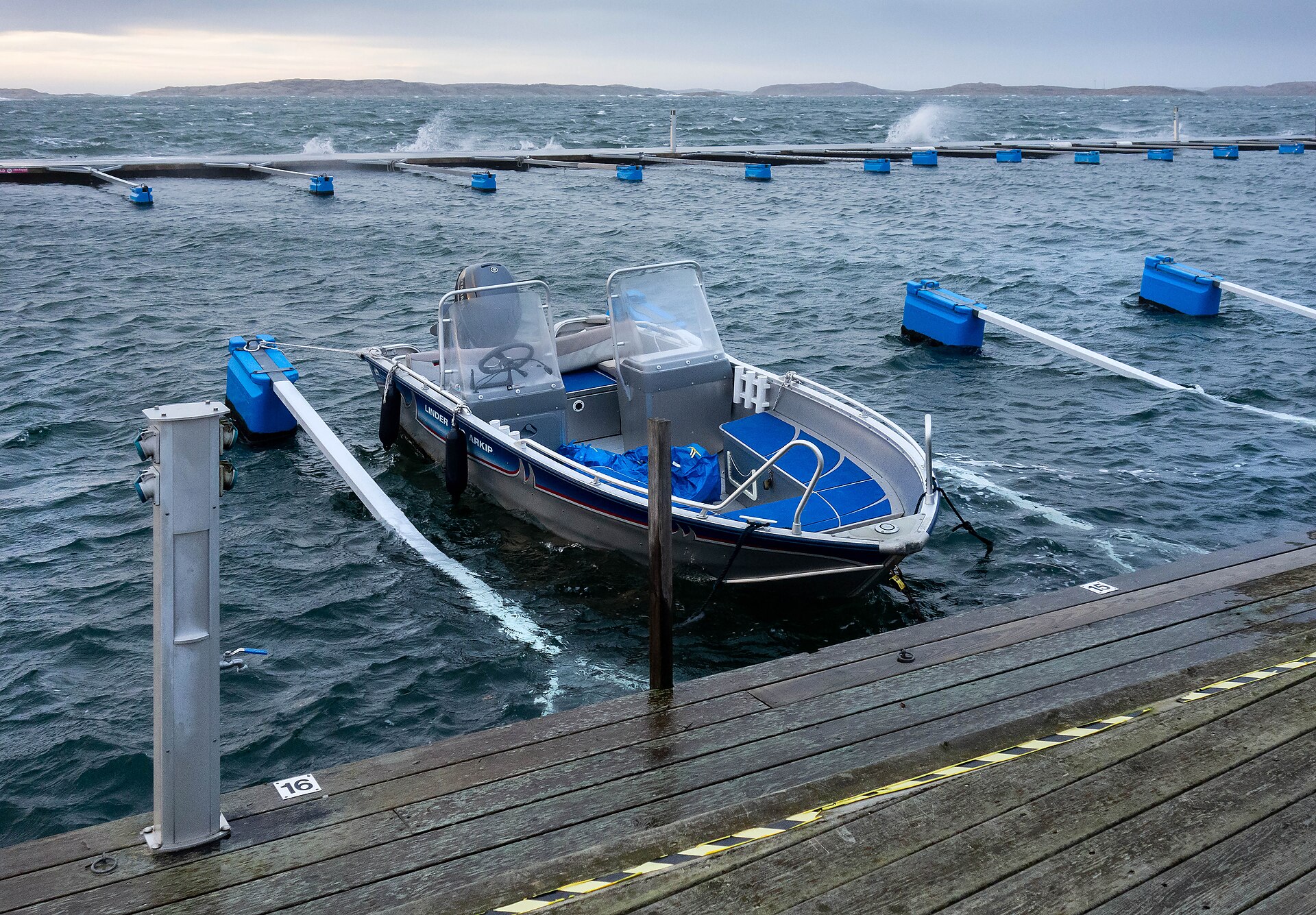 Bateau à moteur le long d’un ponton, mer un peu formée.